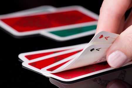 poker: Human hand holding two aces in poker game, cards in background Stock Photo