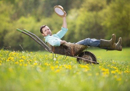 28172062-young-male-farmer-is-relaxing-in-wheelbarrow-on-the-green-meadow.jpg
