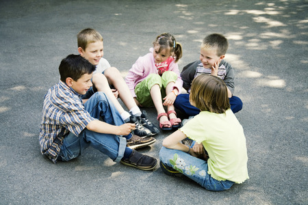 recess: Children sitting in a circle playing Stock Photo