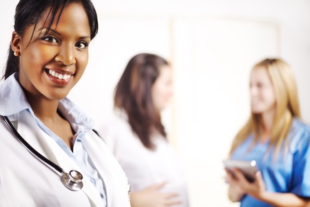 Portrait of a doctor with one of his co-workers talking with a patient in the background Stock Photo