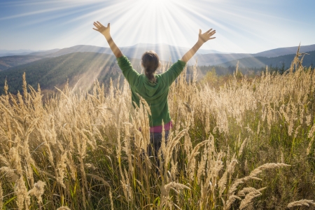 gratitude: Happy young girl enjoying the beauty of sunny autumn day high in the mountains