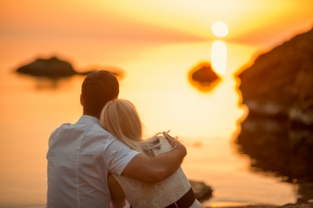 love hug: couple sitting and watching the sun on the beach at sunrise Stock Photo
