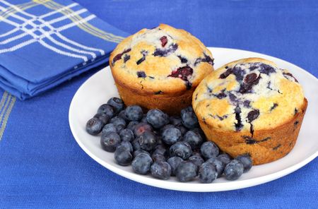blueberry muffin: Delicous Healthy fresh blueberries on a plate with fresh baked blueberry muffins. Close up with copy space available. Stock Photo