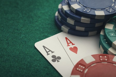 poker: Stack of chips and two aces on the table on the green baize - poker game concept
