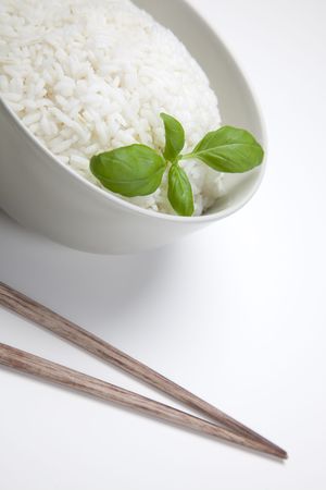 A bowl of perfectly cooked, plain Basmati rice, in an Asian style bowl, with a garnish of Thai Basil