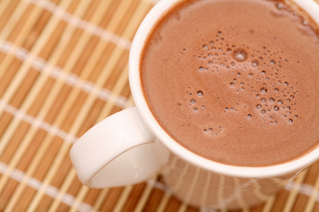 hot chocolate drink: Cup of cocoa with milk on bamboo napkin. Close-up. Stock Photo