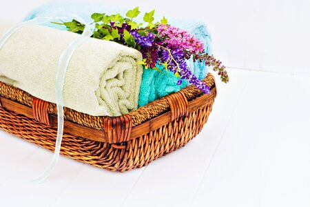OLER ROPA LIMPIA: Cesta de lavandería con toallas limpias frescas y un ramo de flores en un beadboard blanco. Foto de archivo