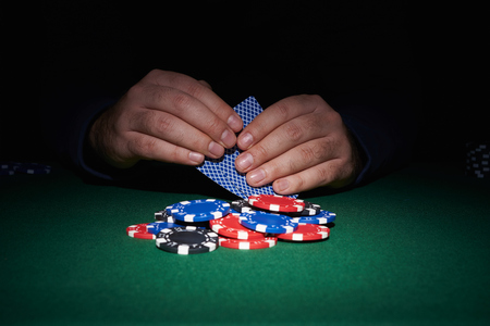 poker: Poker chips on table with hands and cards in casino with black background