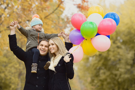 balloon: happy family with little child and air-balloons, outing in autumn park Stock Photo