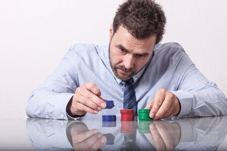 poker: Mature man with poker chips on glass table, sorting stacks Stock Photo