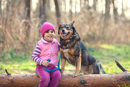 Niña feliz, sentada, con su perro, en el bosque. Foto de archivo. Niña feliz, sentada, con su perro, en el bosque. Foto de archivo.