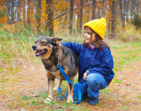 Niña feliz que juega con el perro grande en el bosque en otoño. Foto de archivo. Niña feliz que juega con el perro grande en el bosque en otoño. Foto de archivo.