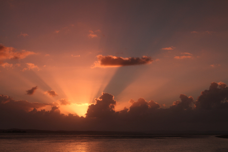 Hervey bay sunrise with sun rays coming up from behind low cloud