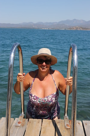 A buxom mature english lady getting out of the sea using ladders on the jetty while Buxom Stock Photos And Images - 123RF