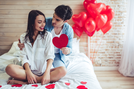 Beautiful young couple in bedroom. Celebrating Saint Valentines Day.