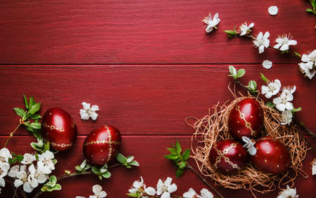Oeufs de pâques et fleurs blanches printanières sur fond de bois rouge de pâques avec espace de copie