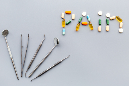 歯痛 歯の痛み 歯科治療の恐怖 歯科医の道具の近くに錠剤が並ぶ言葉の痛み 灰色の背景上図コピースペース の写真素材 画像素材 Image