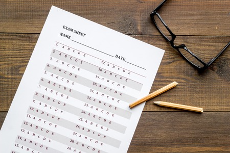 On the exam. exam sheet, answer near glasses and pencil on dark wooden background top view Stock Photo