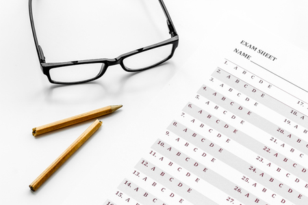 Take the exam. exam sheet near glasses and pencil on white background