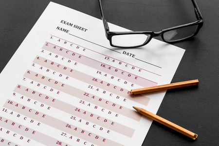 Take the exam. exam sheet near glasses and pencil on black background