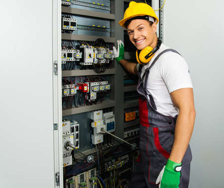 factory production operator cheerful electrician in a safety hat on a factory stock photo - Production Operator factory production operator cheerful electrician in a safety hat on a factory stock photo - Production Operator