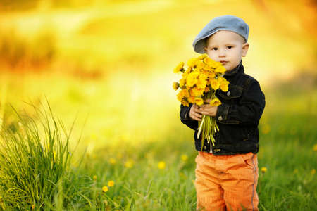 cute little boy with dandelions Фото со стока