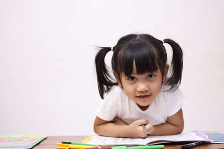Cute adorable little asian baby girl with pony tail hair looking at camera and smiling, happy joy excited expression when learning at home
