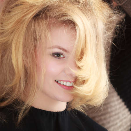美容院で金髪のウェーブのかかった髪を持つ美しい笑みを浮かべて少女 ヘアスタイリスト コーミング女性のクライアント 理髪美容室の若い女性 髪型 の写真素材 画像素材 Image