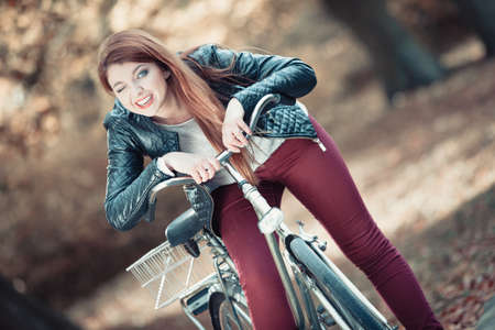 屋外の自然をサイクリング リラックス ファッションのコンセプト 自転車でファッショナブルな女の子 赤毛の女性の自転車とつながる秋の公園を散歩が身なり の写真素材 画像素材 Image