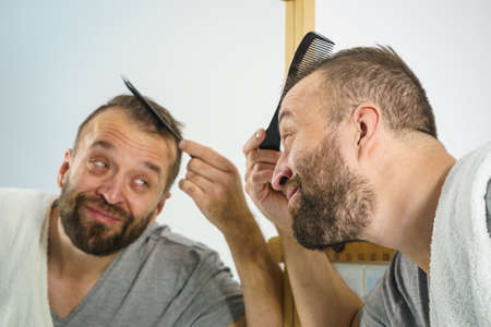 Adult Man Standing In Front Of The Bathroom Mirror Brushing His