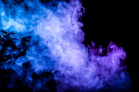Clubs of colored smoke of blue and pink color on a black isolated background in the form of soft clouds from the vape