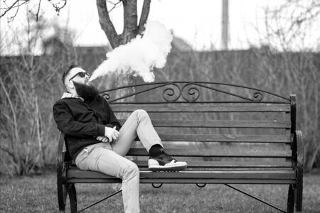 アーク プラズマ蒸着法 大規模な髭とサングラスでオシャレな髪型とか残酷な青年は 都市公園の赤いベンチで電子タバコを吸います 蒸気の雲 ライフ スタイル の写真素材 画像素材 Image アーク プラズマ蒸着法 大規模な髭とサングラスでオシャレな髪型とか残酷な青年は 都市公園の赤いベンチで電子タバコを吸います 蒸気の雲 ライフ スタイル の写真素材 画像素材 Image