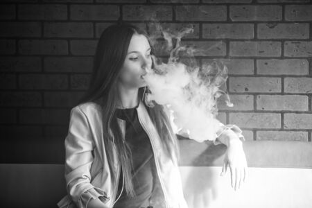 Vaping teenager. young pretty white girl smoking an electronic cigarette in vape bar. bad habit. black and white.