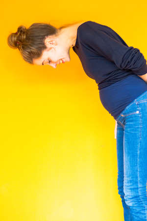 pregnant young woman standing in front of orange background Stock Photo
