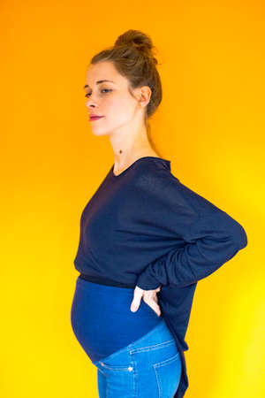 pregnant young woman standing in front of orange background Stock Photo