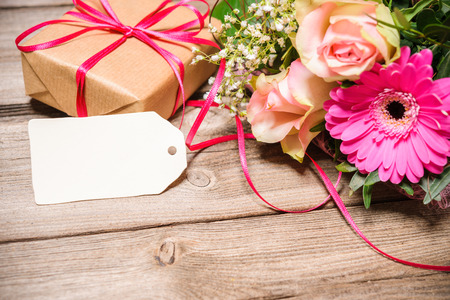 Bunch of flowers with an empty tag on wooden background