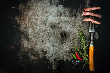 Slices of beef steak on meat fork on dark background