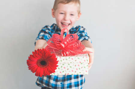 Glückliche freundliche kleiner Junge mit roter Blume und Geschenk-Box in einem Banner