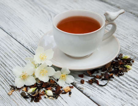 Cup of tea with jasmine flowers on a wooden background