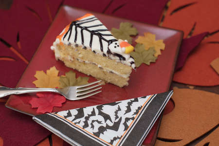 オレンジと黒のアイシングとキャンディ幽霊 赤色のプレート上に添えてフォークと Hallowen ケーキのつや消しホワイト の写真素材 画像素材 Image