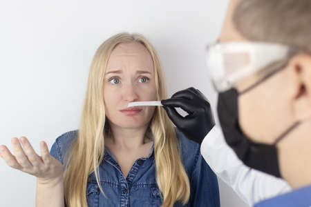 The girl complains to the doctor about the loss of smell. the doctor conducts a sense of smell test. diagnostics of covid-19. symptoms of the coronavirus. quarantine and isolation. test for sars-cov-2 Фото со стока