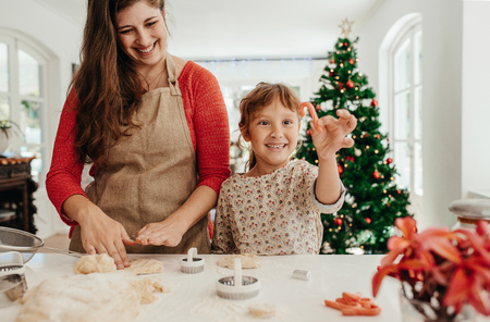 mother and daughter making christmas cookies using dough moulds and cutters little girl holding candy - Making Christmas Cookies mother and daughter making christmas cookies using dough moulds and cutters little girl holding candy - Making Christmas Cookies
