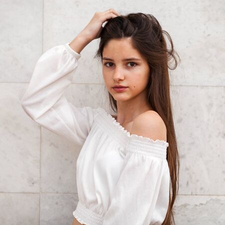 Closeup portrait of a young beautiful girl on a background of a white marble wall - 130042577