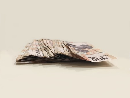 A pile of 500 pesos mexican bank notes over a white desk Stock Photo