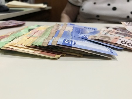 Many mexican pesos bills spread over a beige colored desk inside a small business office
