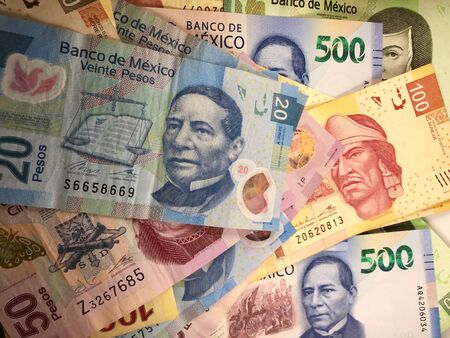 Many mexican pesos bills spread randomly over a flat surface Stock Photo