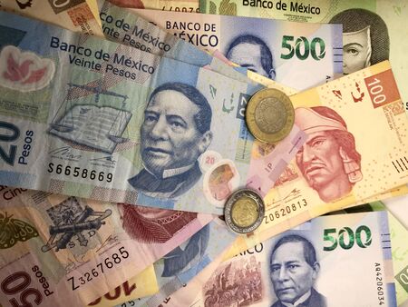 Many mexican pesos bills spread randomly over a flat surface