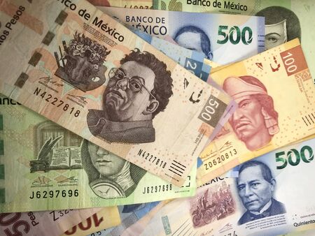 Many mexican pesos bills spread randomly over a flat surface