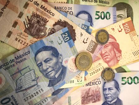 Many mexican pesos bills spread randomly over a flat surface