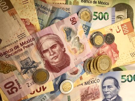 Many mexican pesos bills spread randomly over a flat surface